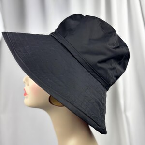Pu&ograve; includere: Cappello da sole nero con tesa larga e fascia intorno alla corona. Il cappello &egrave; realizzato in un materiale liscio. La tesa ha un design cucito. Un accessorio elegante per la protezione solare.
