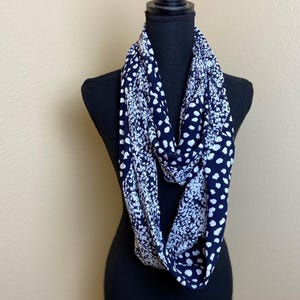 May include: A black and white infinity scarf with a floral and polka dot pattern.