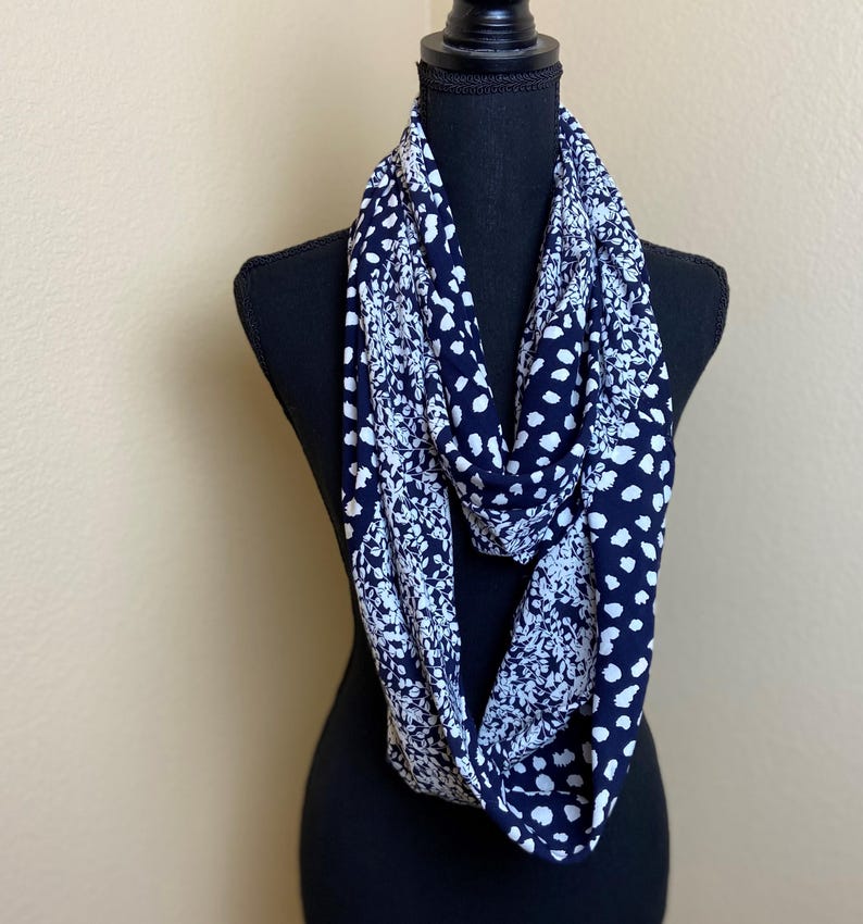 May include: A black and white infinity scarf with a floral and polka dot pattern.