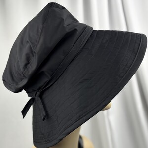 Pu&ograve; includere: Un cappello da sole nero con tesa larga e corona strutturata. Il cappello presenta un dettaglio a fiocco sul lato ed &egrave; realizzato in un tessuto liscio e opaco. La tesa ha un design trapuntato cucito.