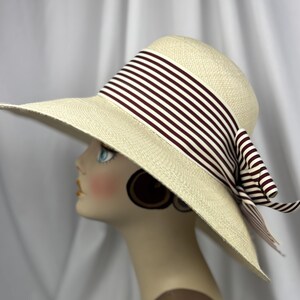 Pu&ograve; includere: Cappello da sole color crema a tesa larga, ornato da un nastro e un fiocco a righe marroni e bianche. Il cappello &egrave; realizzato in materiale tessuto e presenta un design classico. Ideale per la protezione solare e la moda.