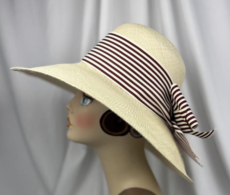 Pu&ograve; includere: Cappello da sole color crema a tesa larga, ornato da un nastro e un fiocco a righe marroni e bianche. Il cappello &egrave; realizzato in materiale tessuto e presenta un design classico. Ideale per la protezione solare e la moda.