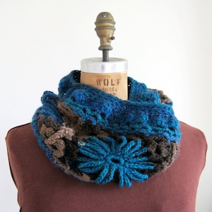 Puede incluir: Un calentador de cuello de ganchillo en marrón, azul y turquesa con un gran acento de flor turquesa.