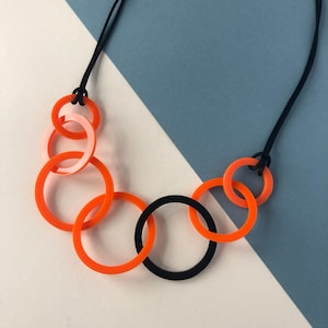 Orange and black round link mid-length acrylic necklace.