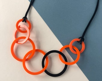 Orange and black round link mid-length acrylic necklace.