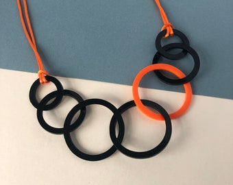 Collier mi-long en acrylique à maillons ronds noir et orange.