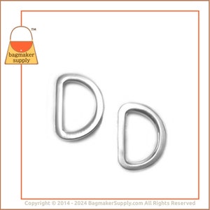 May include: Two silver D-rings, also known as D rings or D-shaped rings, are shown against a white background. These metal rings are commonly used in crafting, sewing, and leatherwork.
