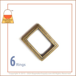May include: Six antique gold metal D-rings. The rings are rectangular with a smooth, slightly textured finish.