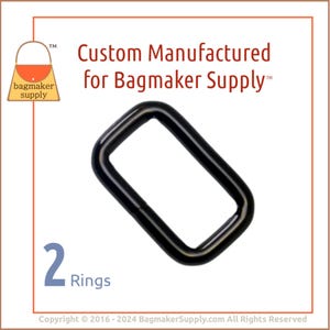 Puede incluir: Dos anillos en D de metal negro. Los anillos tienen un diámetro de aproximadamente 2,5 cm. La imagen incluye el texto "Custom Manufactured for Bagmaker Supply™".