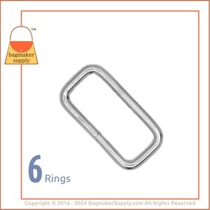 May include: A single, shiny, silver-colored rectangular ring. The ring is made of metal and has rounded corners. The number "6" and the word "Rings" are displayed in the lower left corner.