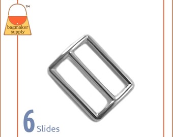 May include: Silver metal slider buckle for bags or straps. The buckle is rectangular with two parallel bars. The text "6 Slides" is visible below the buckle.