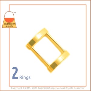 May include: Two gold metal rings, each with a circular shape, connected to form a rectangular frame. The rings are commonly used for attaching straps or handles to bags or other leather goods.