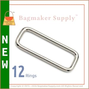 May include: A silver-toned metal rectangular ring with rounded corners. The image includes the text Bagmaker Supply, NEW, and 12 Rings. The metal surface is smooth and reflective, forming a continuous loop for bag hardware applications.