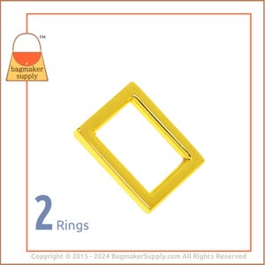 May include: Two gold-colored metal rings, each with a rectangular shape. The rings are shown against a white background.