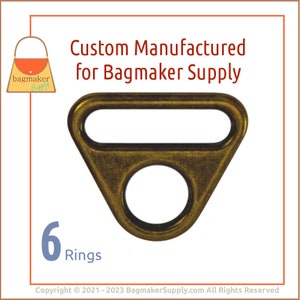 May include: Six antique gold-toned metal D-rings. The rings are triangular shaped with a round hole in the center. The rings are designed for use in bag making.