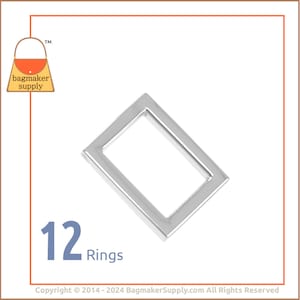 May include: Twelve silver metal rings, each with a rectangular shape. The rings are arranged in a pile, with the top ring facing the camera.