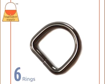 May include: A single, dark gray D-ring, made of metal, is centered on a white background. The ring has a square shape with rounded corners. The number "6" and the word "Rings" are in the lower left corner. The Bagmaker Supply logo is in the upper left corner.
