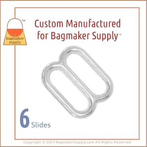 Puede incluir: Hebilla deslizante de metal plateado con dos lazos. La hebilla está diseñada para su uso en la fabricación de bolsos. El texto "Custom Manufactured for Bagmaker Supply™" está impreso sobre la hebilla. El texto "6 Slides" está impreso debajo de la hebilla.