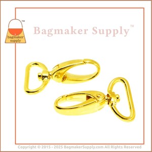 May include: Two gold-tone metal swivel clasps, each with a D-ring and a hook. The clasps are commonly used for attaching straps or chains to bags or other accessories.