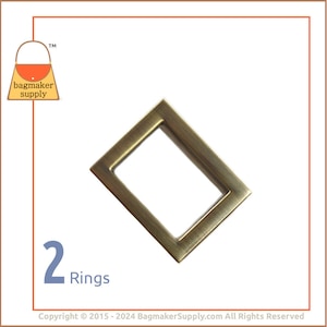 Puede incluir: Dos anillos de metal dorado antiguo, cada uno con una abertura rectangular. Los anillos están dispuestos en forma de diamante.