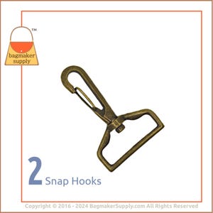 May include: Two antique brass snap hooks. The hooks are made of metal and have a spring-loaded clasp. They are commonly used for attaching straps, leashes, or other accessories to bags, purses, or other items.