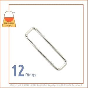 May include: Twelve silver metal rings, each with a rectangular shape. The rings are approximately 2.5 cm in length and 1.25 cm in width.
