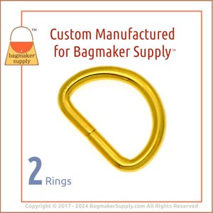 May include: Two gold-colored metal D-rings. The rings are approximately 1 inch in diameter. The image includes the text "Custom Manufactured for Bagmaker Supply™".