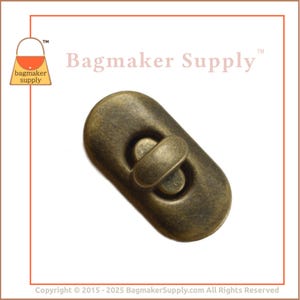 May include: A brass-colored, oval-shaped, magnetic snap closure for bags and purses. The snap has a textured finish and a slightly raised, circular design in the center.