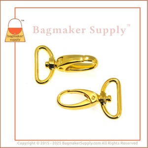 May include: Two gold-tone metal swivel clasps, each with a D-ring and a hook. The clasps are commonly used for attaching straps or chains to bags or other accessories.