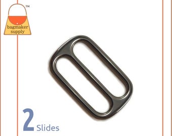May include: A dark gray metal slide with two openings, designed for bagmaking. The slide is rectangular with rounded edges and is set against a white background. The text "2 Slides" is visible in the lower left corner.