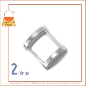 May include: Two silver metal rings, each with a rounded, slightly curved shape. The rings are connected by a straight metal bar.
