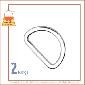 May include: Two silver D-rings, a type of metal hardware used in crafting and sewing projects. The rings are shown against a white background.