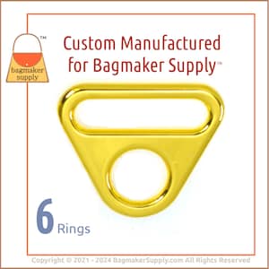 May include: Six gold-toned metal D-rings with a triangular shape and a round hole in the center.  Custom Manufactured for Bagmaker Supply.