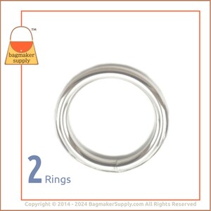 May include: Two silver metal rings, each with a diameter of approximately 1 inch. The rings are smooth and shiny.