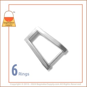 May include: Six silver metal rings, each with a rectangular shape and a small opening. The rings are arranged in a row, with the opening facing the viewer.