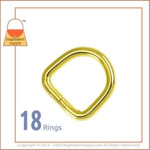 May include: A close-up of 18 gold-colored metal rings. The rings are D-shaped and have a smooth finish.