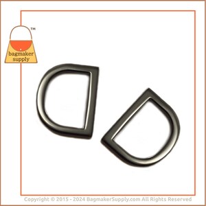 May include: Two black metal D-rings, each with a rounded top and a straight bottom. The rings are about 1.5 inches in diameter.