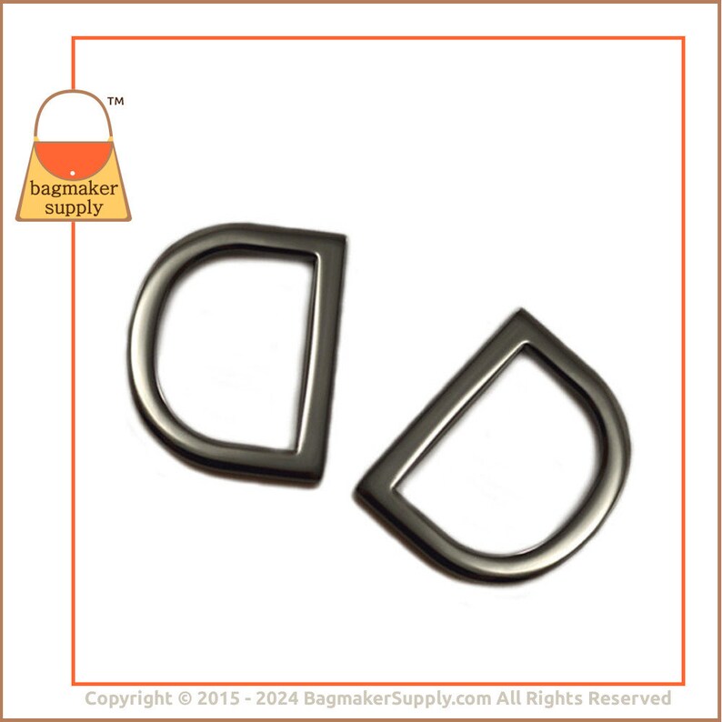 May include: Two black metal D-rings, each with a rounded top and a straight bottom. The rings are about 1.5 inches in diameter.