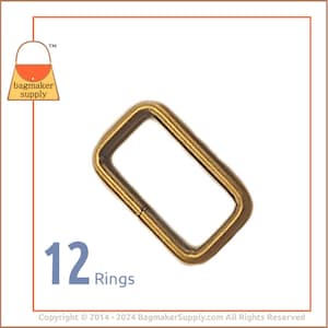 May include: Twelve gold metal rings, each with a rectangular shape. The rings are ideal for attaching to straps, handles, or other accessories.