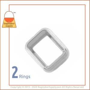 Puede incluir: Dos anillos de metal plateado, cada uno con forma cuadrada y un acabado liso y pulido. Los anillos están diseñados para su uso en proyectos de artesanía y costura.