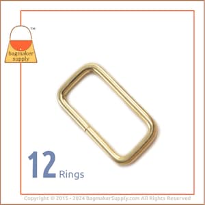 May include: Twelve gold metal rings, each with a rectangular shape. The rings are approximately 1 inch in length and 1/2 inch in width.
