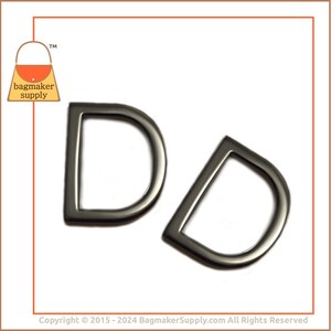 May include: Two silver-toned D-rings, each with a smooth, rounded edge. The rings are isolated on a white background.