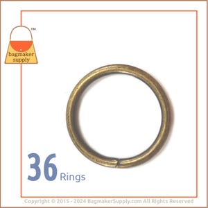 May include: A close-up of 36 gold-toned metal rings. The rings are round and have a smooth finish. They are perfect for attaching to bags, purses, or other accessories.