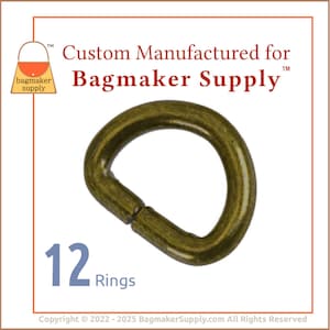 May include: An antique brass-colored D-ring for bagmaking. The image shows a single ring with a rounded D-shape. The text "12 Rings" is visible. The text "Custom Manufactured for Bagmaker Supply" is also visible.