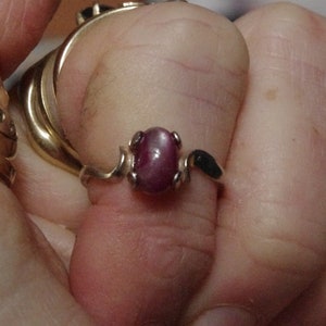 May include: A silver ring with a pink star-shaped gemstone set in a prong setting. The ring has a simple band and a delicate design.