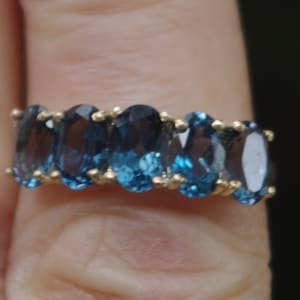 Puede incluir: Un anillo de banda de oro con seis piedras azules ovaladas.