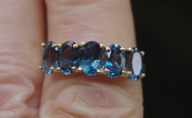 Puede incluir: Un anillo de banda de oro con seis piedras azules ovaladas.