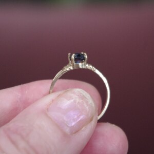 May include: A gold ring with a dark blue gemstone set in a simple, elegant design.
