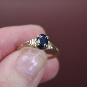 May include: A gold ring with a dark blue oval-shaped gemstone.
