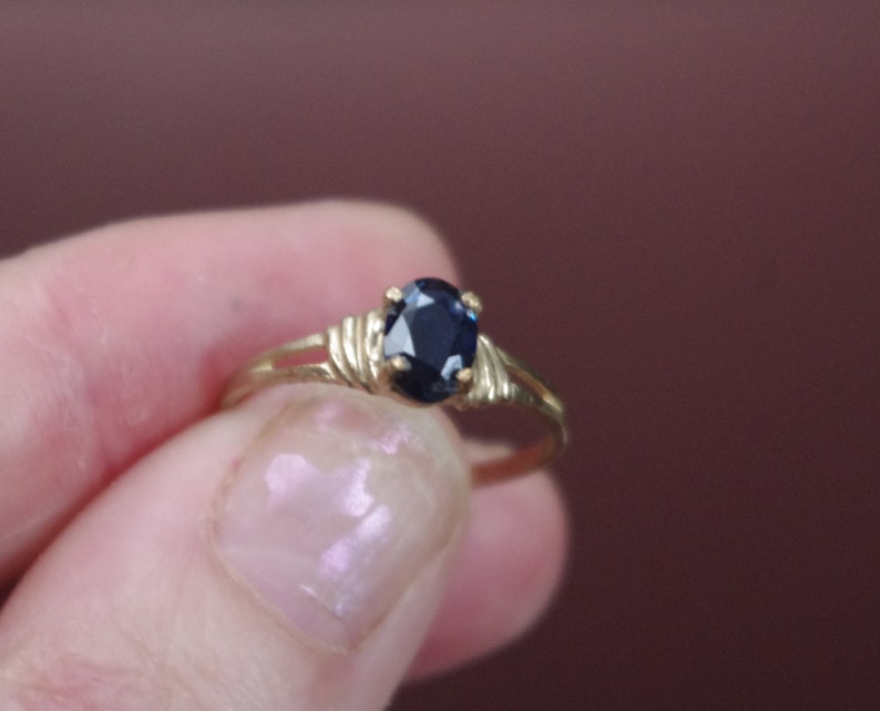 May include: A gold ring with a dark blue oval-shaped gemstone.